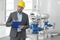 Young male manager writing on clipboard in industry