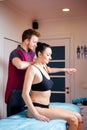 Young male massage therapist doing Relaxing massage for a girl in black underwear and dark gathered. A patient in the massage room