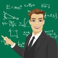 Young male math teacher with piece of chalk standing next to blackboard