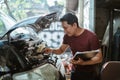 young male mechanic checks brake fluid while holding a clipboard
