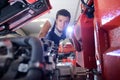 young male mechanic looking at engine with torch