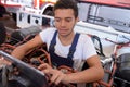 Young male mechanic using tablet while working on industrial vehicle