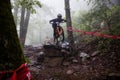 Young male mountain biker jumping over a rocky terrain while navigating a forest trail