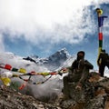 Young male mountaineer with a backpack resting on rocks, with snowy mountain range in the background