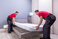 Young Male Movers Placing The Mattress Over The Bed Royalty Free Stock Photo