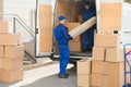 Movers Unloading Rolled Up Rug From Truck