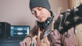 Young male musician composes and records soundtrack playing the guitar using computer, headphones and keyboard Royalty Free Stock Photo