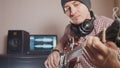 Young male musician composes and records soundtrack playing the guitar using computer, headphones and keyboard Royalty Free Stock Photo