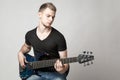 Young male musician playing a six-string bass guitar isolated