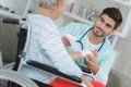 Young male nurse bandaging elderly woman`s wrist