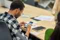 Young male office worker using smartphone while working in the modern office Royalty Free Stock Photo