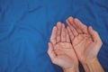 Young male open hands praying top view in dark blue background.