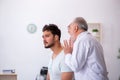 Young male patient with hearing problem visiting old doctor otor Royalty Free Stock Photo