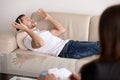 Young male patient lying on couch talking to female psychologist Royalty Free Stock Photo
