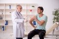 Young male patient visiting old male doctor in vaccination conce Royalty Free Stock Photo