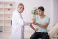 Young male patient visiting old male doctor in vaccination conce Royalty Free Stock Photo