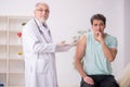 Young male patient visiting old male doctor in vaccination conce Royalty Free Stock Photo