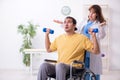 Young male patient in wheel-chair doing physical exercises