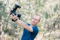 Young male photographer looks wondered to DSLR camera in his hanss on summer day.