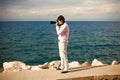 Young male photographer taking photos on professinal camera near sea Royalty Free Stock Photo