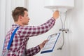 Male Plumber Adjusting Temperature Of Electric Boiler Royalty Free Stock Photo