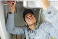 young male plumber performing repair under kitchen sink Royalty Free Stock Photo