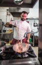 Chef preparing beef fillet steak in a frying pan with exploding flame