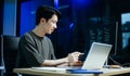 Young male programmer working with tablet and screen displaying code. Modern tech office setup, great for software, coding, IT Royalty Free Stock Photo