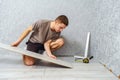 Young male repairman is laying panel of laminate floor indoors on the knees Royalty Free Stock Photo