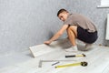 Young male repairman is laying panel of laminate floor indoors on the knees Royalty Free Stock Photo