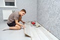 Young male repairman is laying panel of laminate floor indoors on the knees Royalty Free Stock Photo