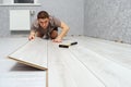Young male repairman is laying panel of laminate floor indoors. Royalty Free Stock Photo