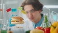 Young male researcher examines a sample of burger labeled E142, E240, E121 and E160. Biolog analyzes the quality of the