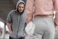 young male robber in hoodie going to steal handbag from