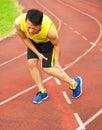 Young male runner suffering from leg cramp on the track