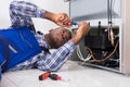 Male Serviceman Working On Fridge With Screwdriver Royalty Free Stock Photo