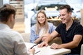 young male shop assistant explaining talking offering buying new car to family Royalty Free Stock Photo