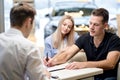 young male shop assistant explaining talking offering buying new car to family Royalty Free Stock Photo