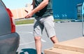 Young male shopper stacks cardboard boxes in the trunk of a car in a supermarket parking lot. Close-up view Royalty Free Stock Photo