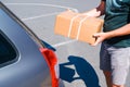 Young male shopper stacks cardboard boxes in the trunk of a car in a supermarket parking lot. Close-up view Royalty Free Stock Photo