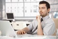 Young male sitting at desk working on laptop Royalty Free Stock Photo