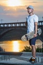 Young male skateboarder on a background of colorful sunset, free space.