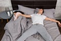 Young male sleeping in free fall position with his girlfriend occupied the whole bed, wearing pajamas