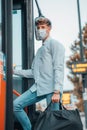 Young male Spanish wearing a facemask carrying a bag while riding up a bus Royalty Free Stock Photo