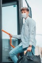 Young male Spanish wearing a facemask carrying a bag while riding up a bus Royalty Free Stock Photo