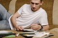 A young male student lying on a couch and using laptop while doing homework.Distance learning,Online learning Royalty Free Stock Photo