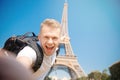 Young male student makes selfie photo with backpack against background of Eiffel Tower in Paris, France. Concept travel