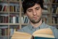 Young male student reading a book in a library. Portrait of male student holding book Royalty Free Stock Photo