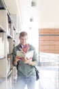 Young male student reading book by shelf at university library Royalty Free Stock Photo