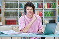 Young male student sitting with laptop with books in college library Royalty Free Stock Photo